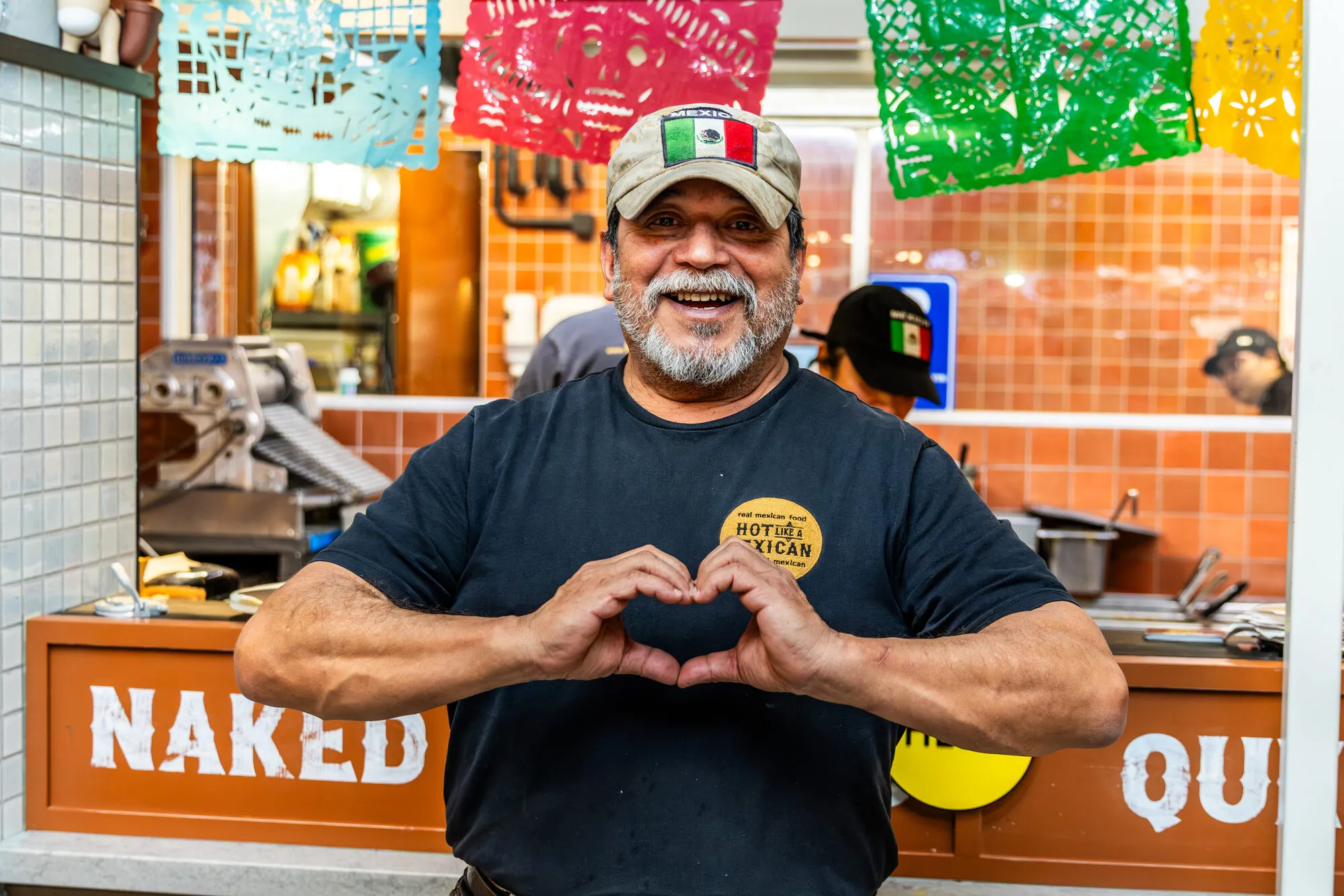 Andrés makes a heart with his hands at the counter